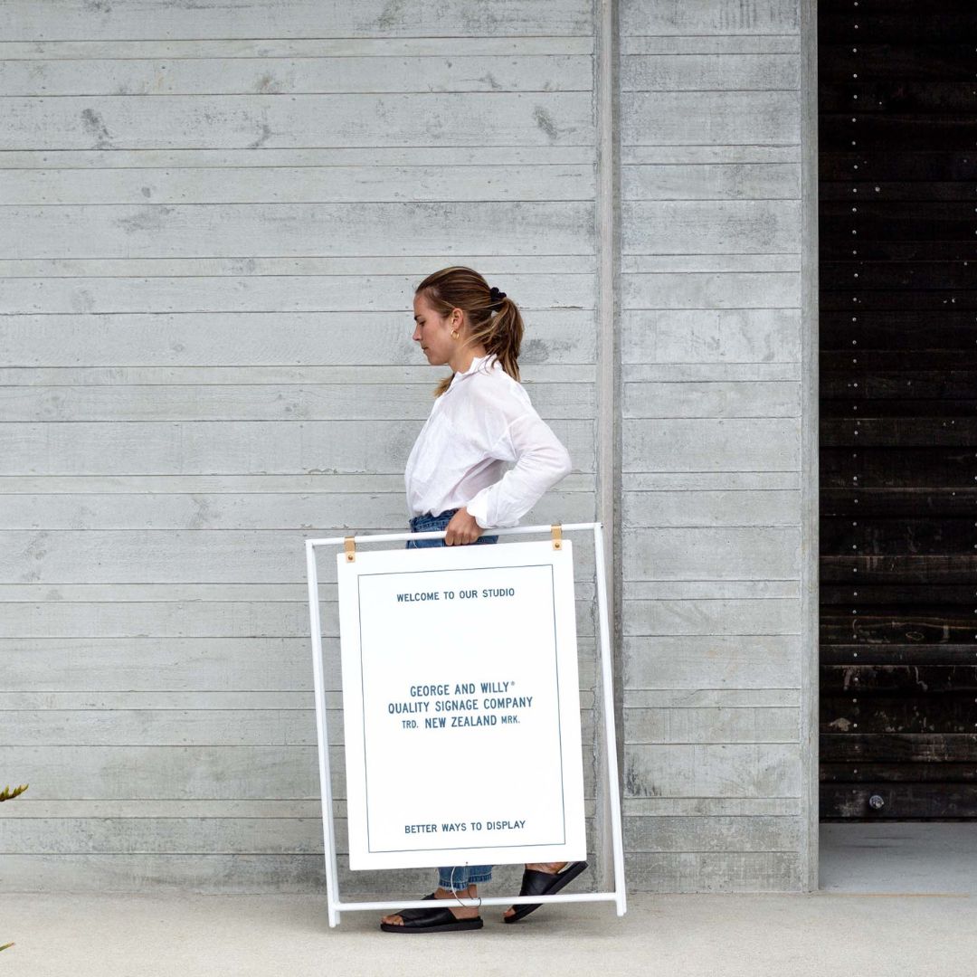 person carrying large a-frame sign outdoors