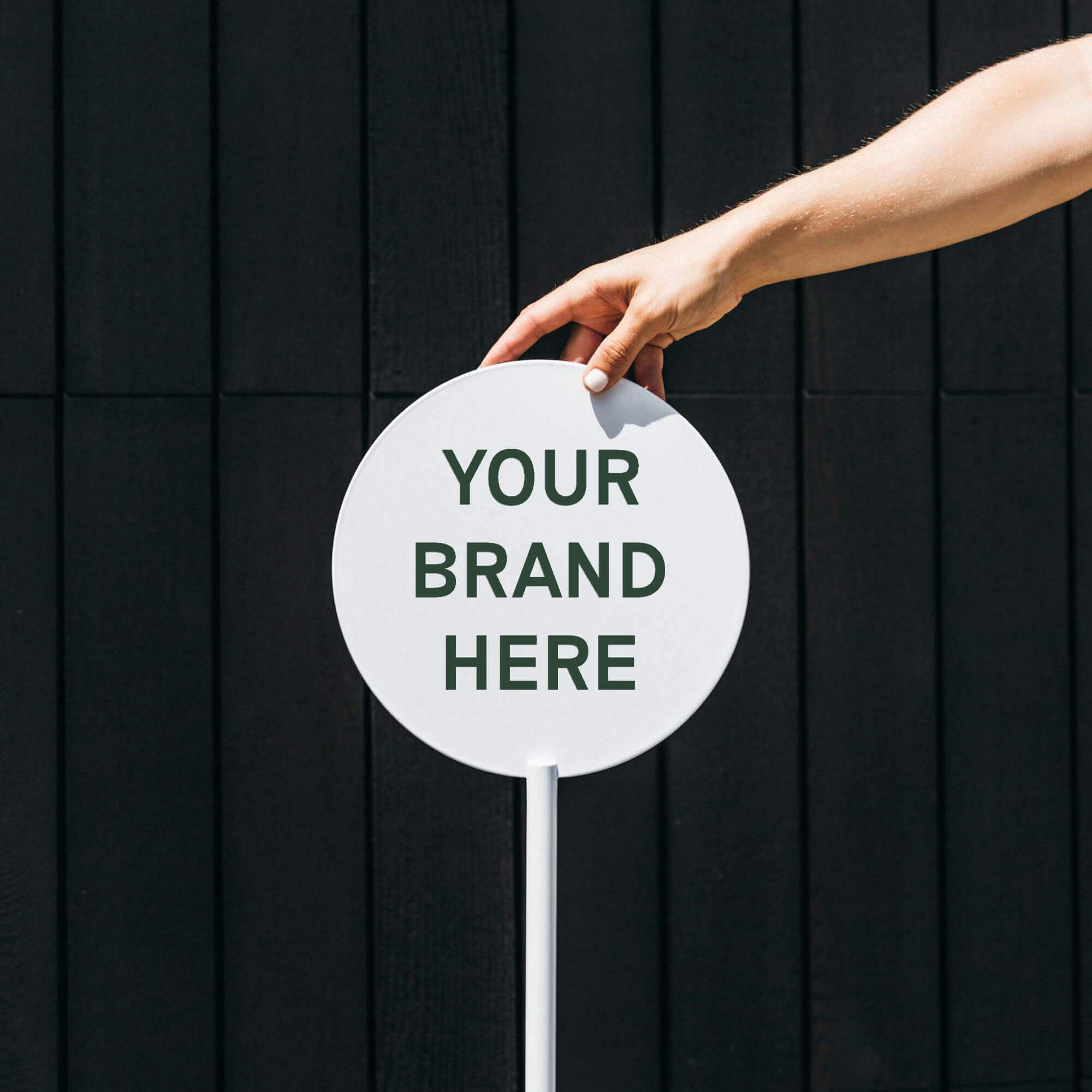 human hand holding a round storefront sign outside