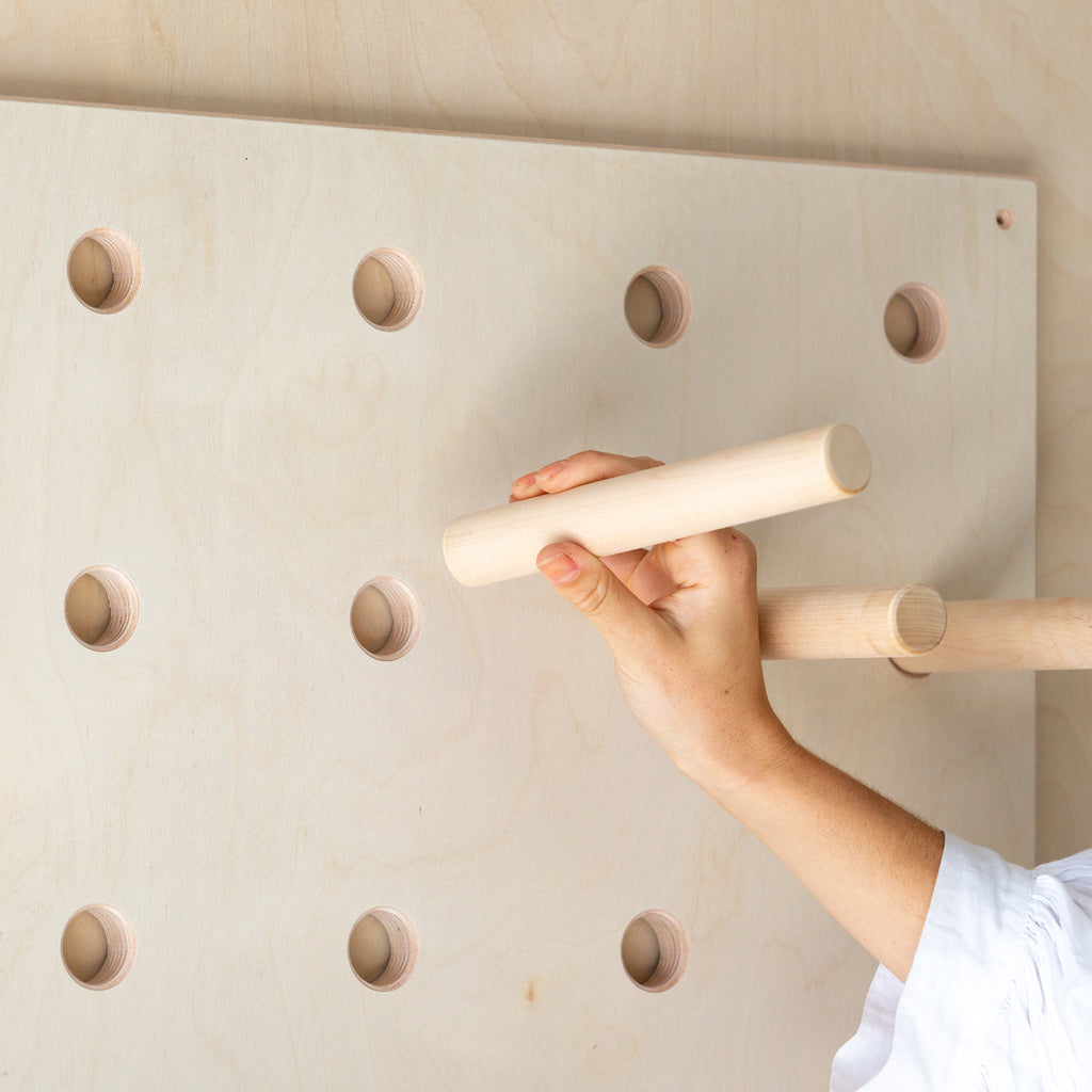 A wooden pegboard with dowel pegs and shelves designed for storing belongings or displaying products in a store
